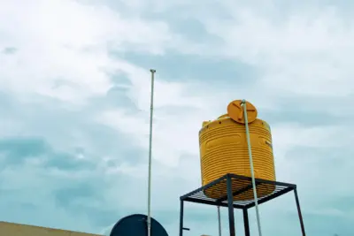 Plastic water tank with secure lid cap on rooftop in India summer sunlight