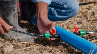 Hands fitting HDPE compression coupler onto irrigation pipe on farm